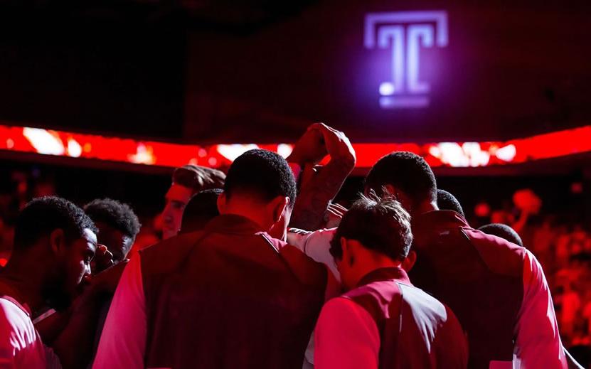 Temple Men's basketball player stand in huddle with arms raised