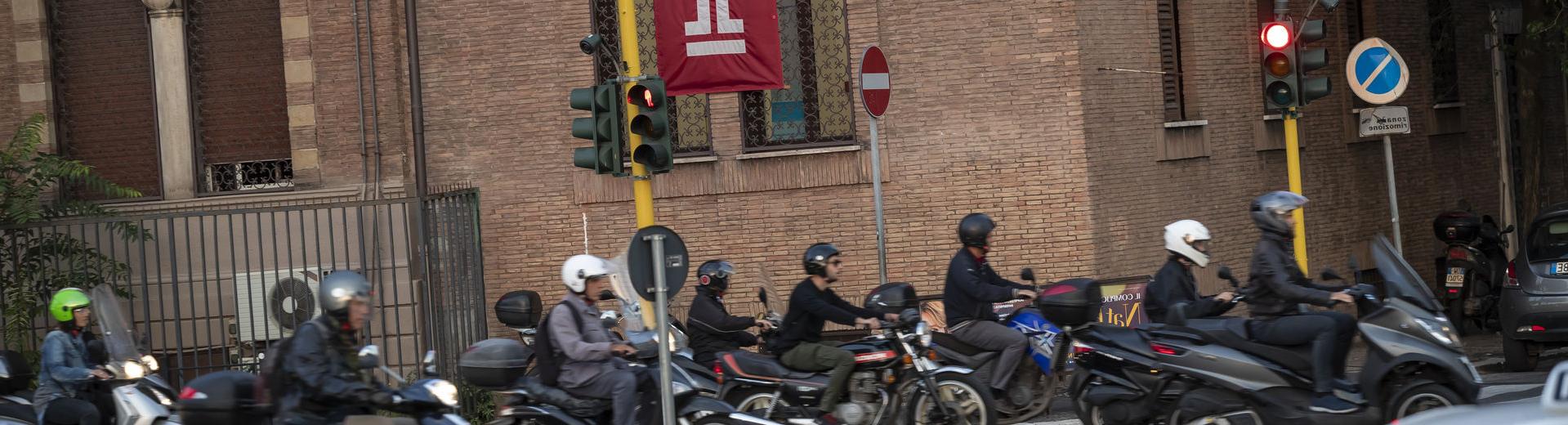 A group of people on motorcycles on an Italian street near Temple Rome.