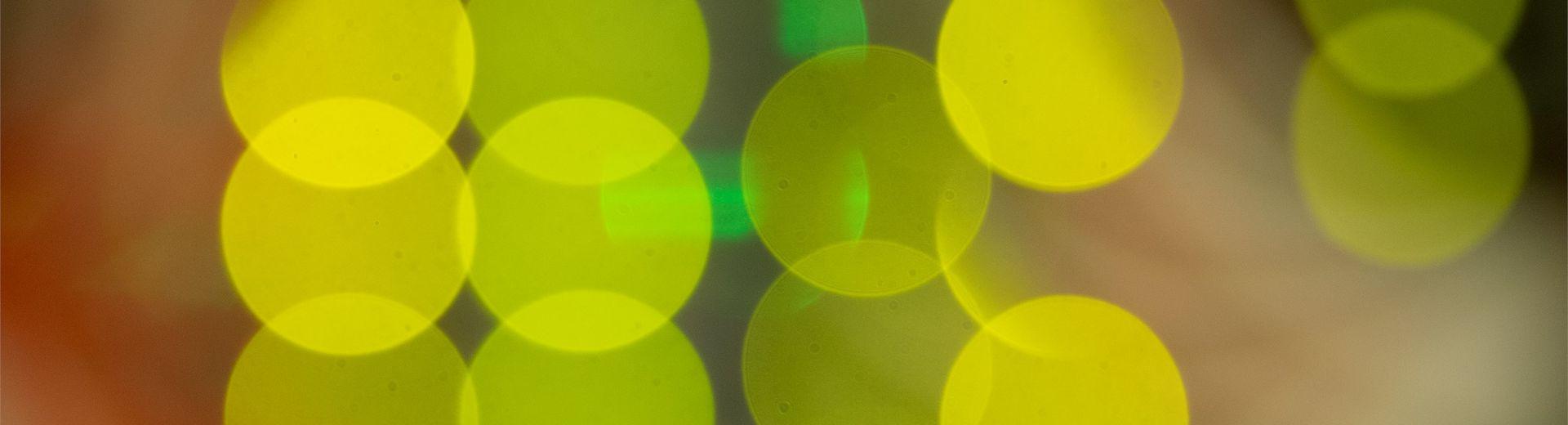 Image is a super close up shot of lights in the back of computer servers resulting in an image of overlapping bright yellow discs of color.