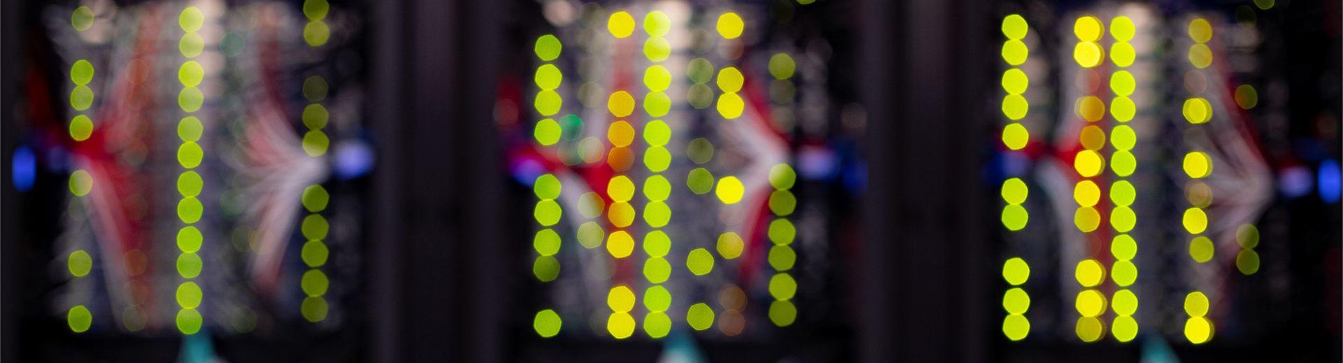 Blurred image of the back of computer servers resulting in a very primary colorscape with columns of bright yellow circles.