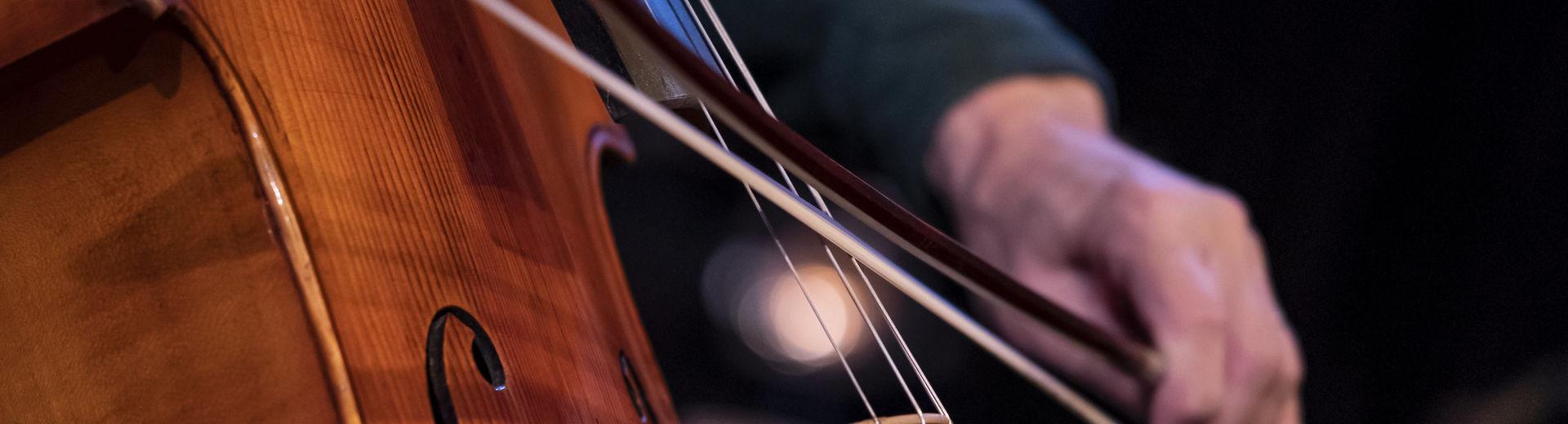 Close up image of a student playing the cello in a performance.
