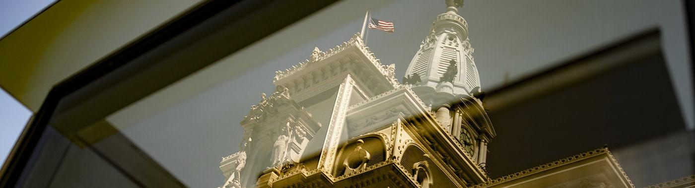 Philadelphia City Hall is seen through a window.